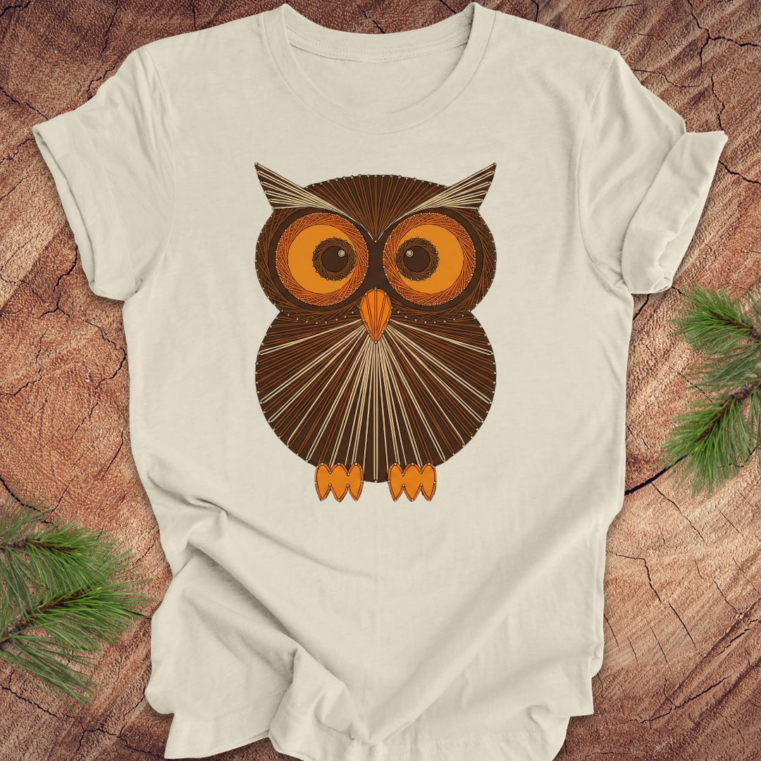 Beige colored t-shirt with a vintage owl design on a wooden surface