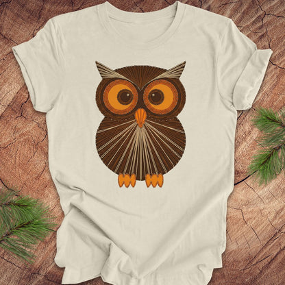 Beige colored t-shirt with a vintage owl design on a wooden surface