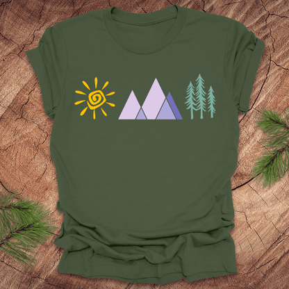 Green t-shirt with sun, mountains, and trees on a wooden surface