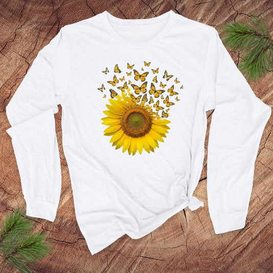 White long-sleeve shirt with a sunflower and butterfly design on a wooden surface.