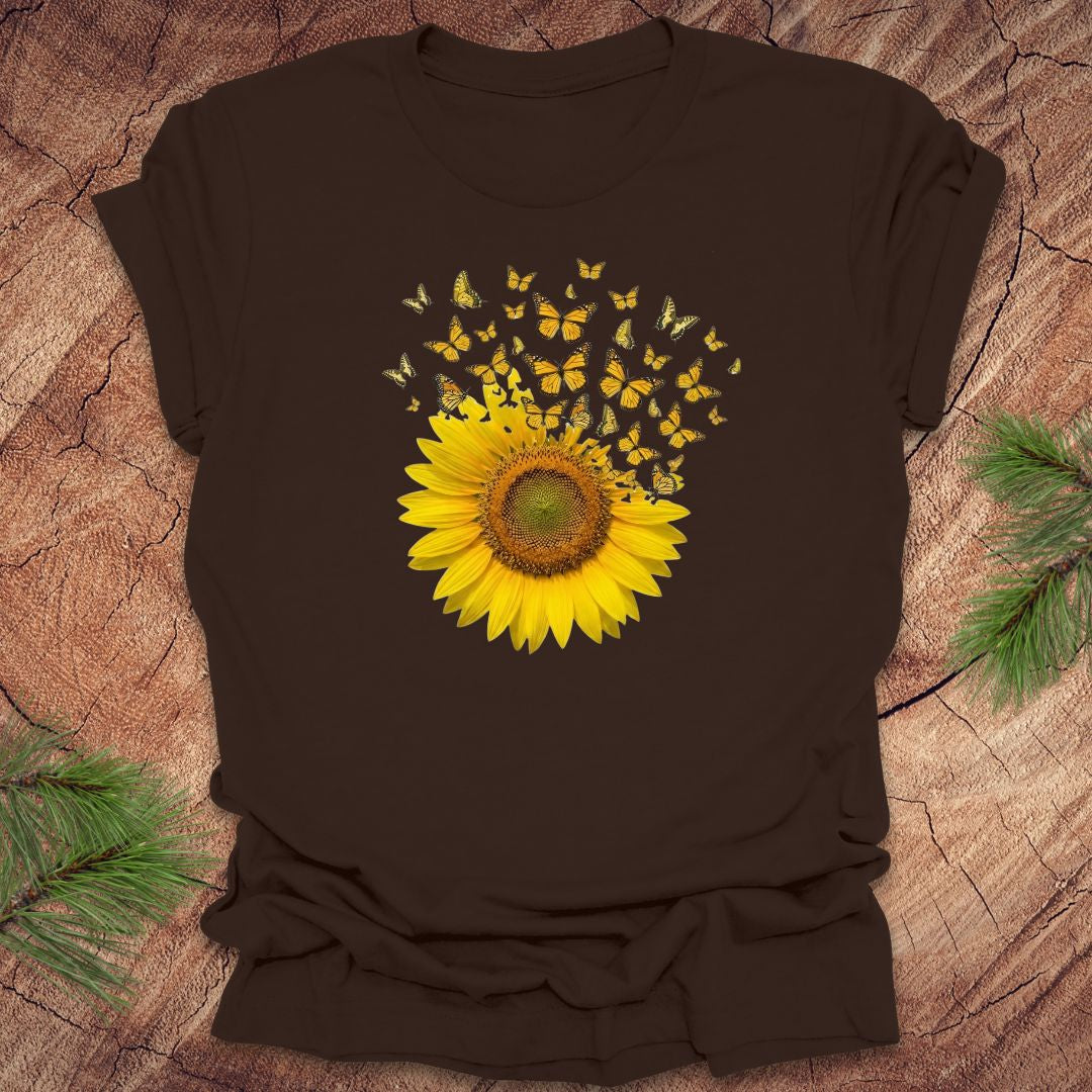 Brown t-shirt with a yellow sunflower and butterflies design on a wooden surface.