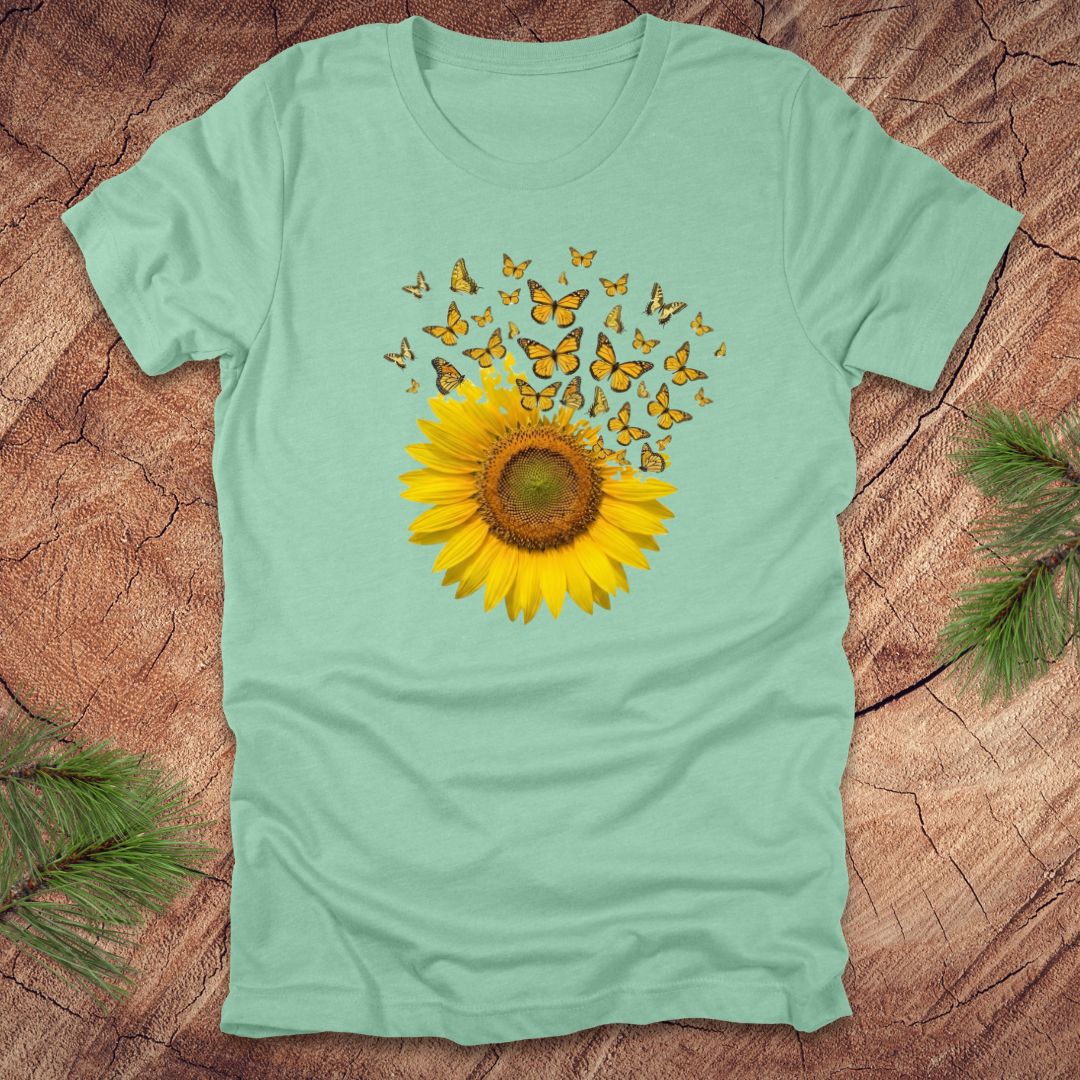 Light green t-shirt with a sunflower and butterfly design on a wooden surface.
