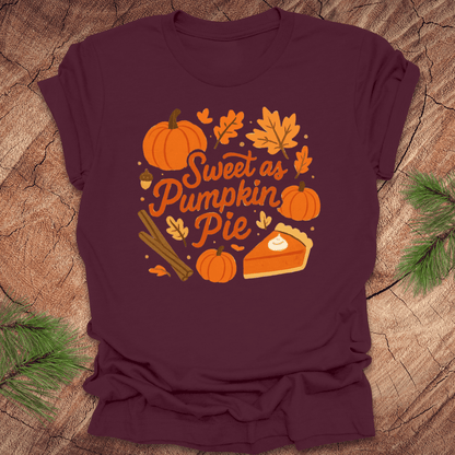 Maroon t-shirt with 'Sweet as Pumpkin Pie' design on a wooden surface with leaves.