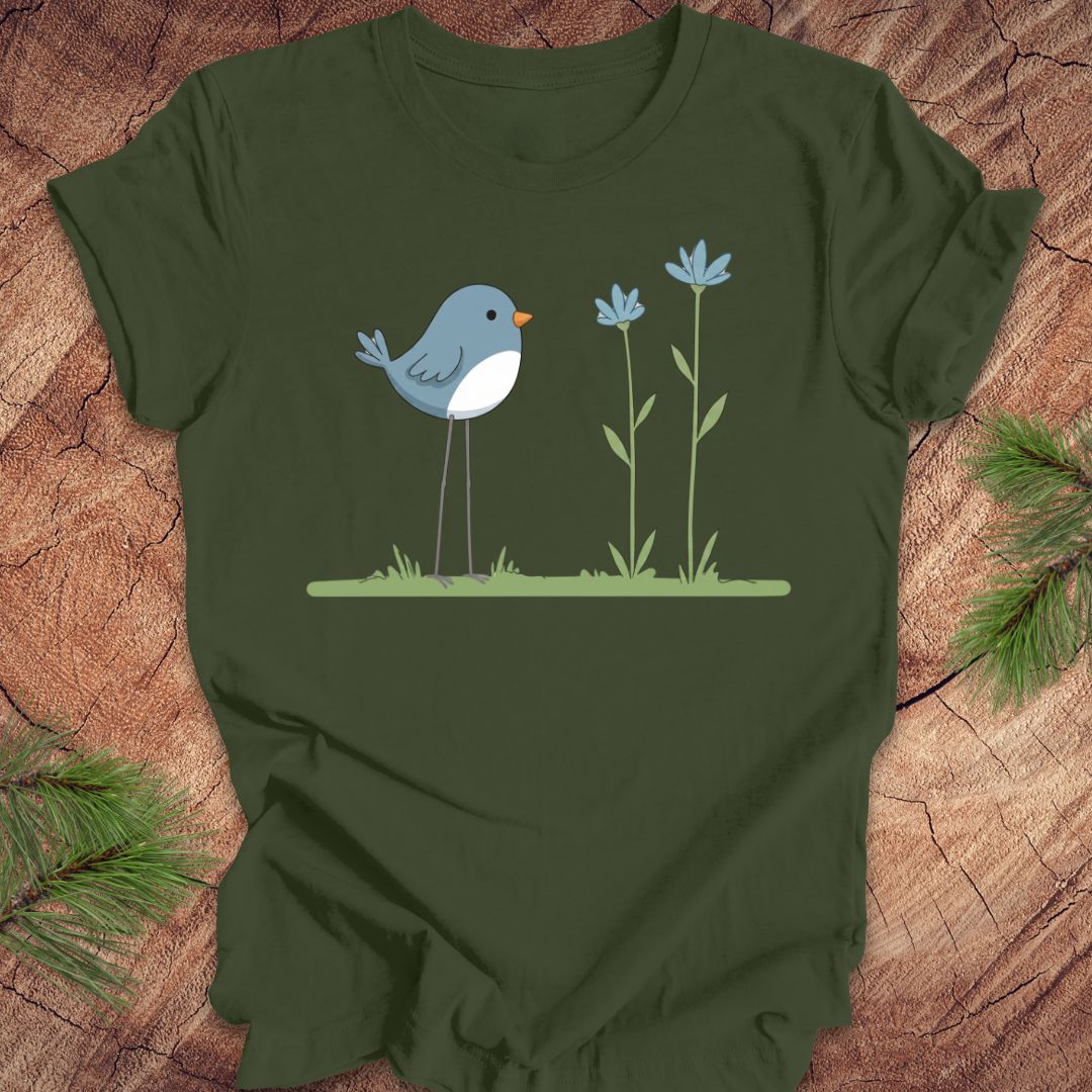 Green t-shirt with a blue bird and flowers design on a wooden surface.