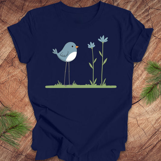 Navy blue t-shirt with a blue bird and flowers design on a wooden surface.