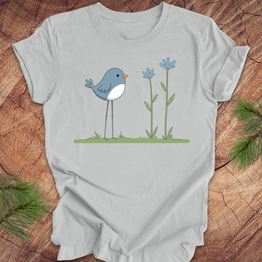 Gray t-shirt with a blue bird and flowers design on a wooden surface.