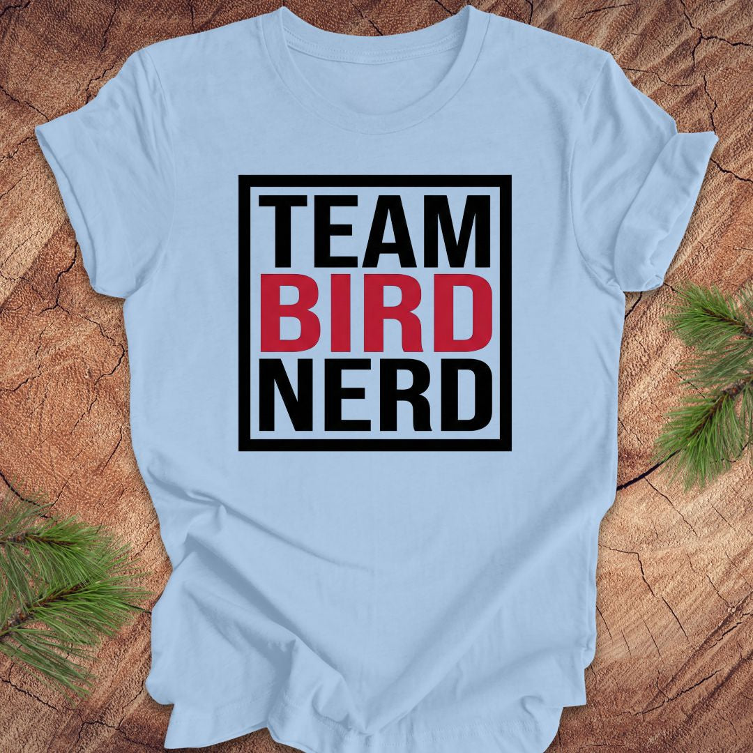 Light blue t-shirt with 'Team Bird Nerd' text on a wooden surface