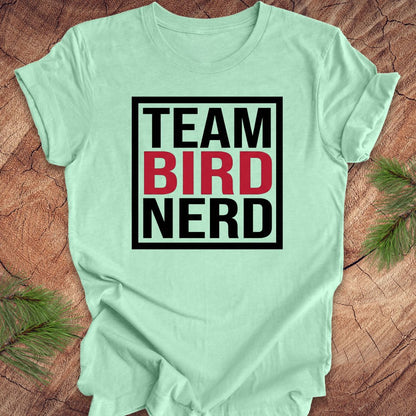 Light green t-shirt with 'Team Bird Nerd' text on a wooden surface