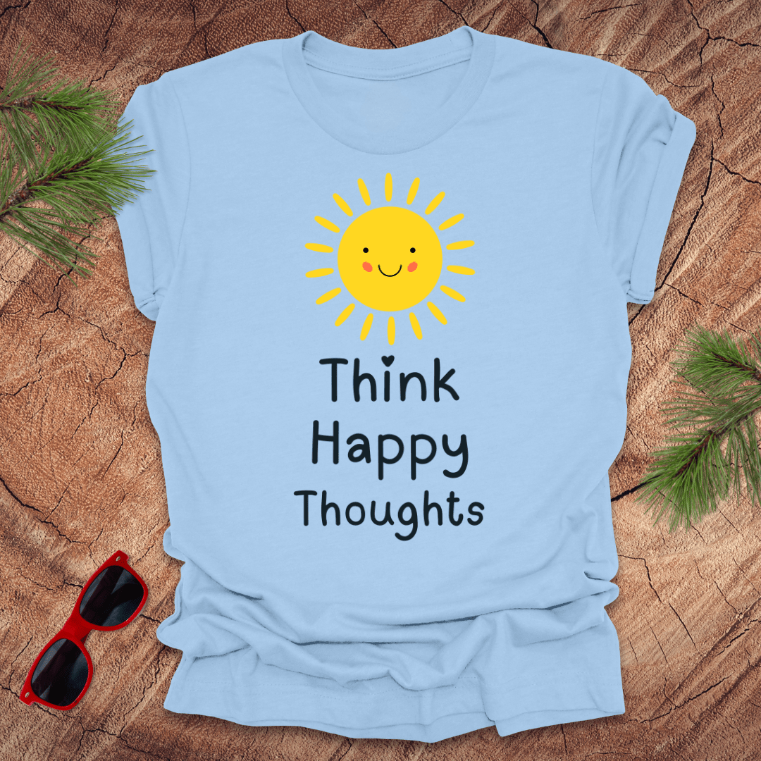 Light blue t-shirt with a sun and text design on a wooden surface with sunglasses and greenery.