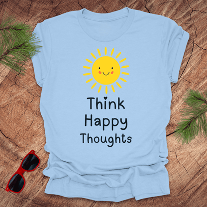 Light blue t-shirt with a sun and text design on a wooden surface with sunglasses and greenery.