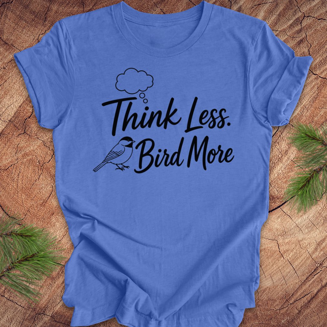 Blue t-shirt with 'Think Less. Bird More' text on a wooden surface