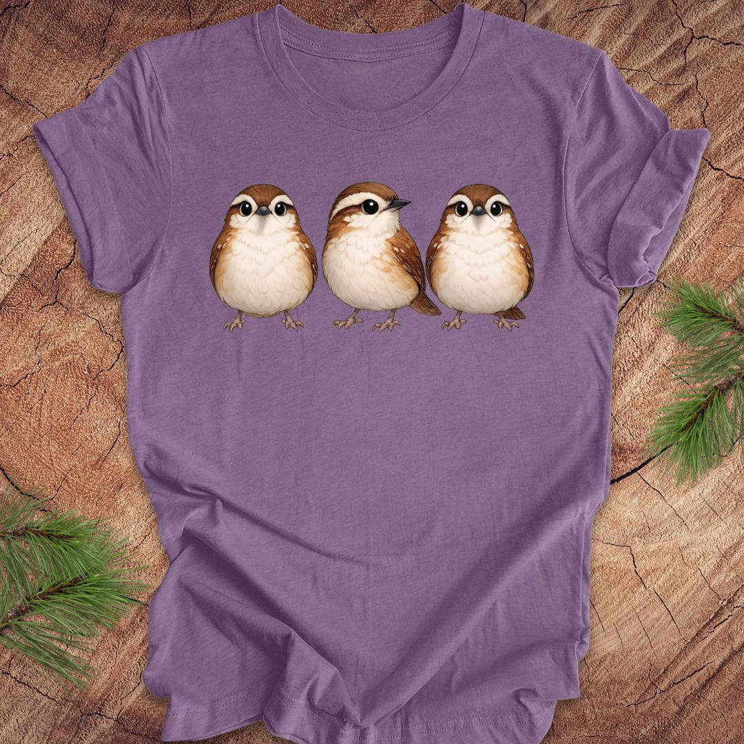 Purple t-shirt with three carolina wren birds on a wooden surface