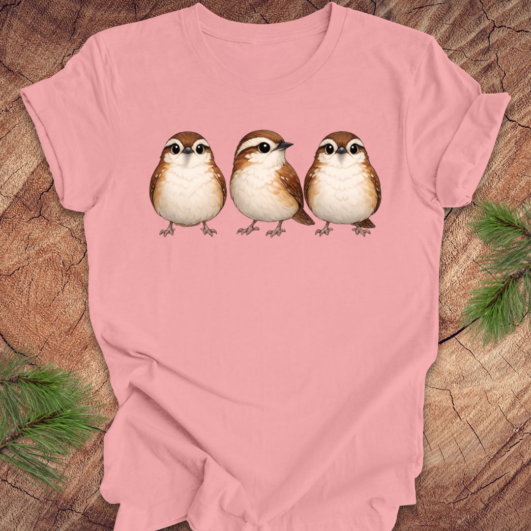 Pink t-shirt with three carolina wren birds on a wooden surface