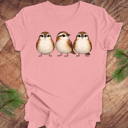 Pink t-shirt with three carolina wren birds on a wooden surface