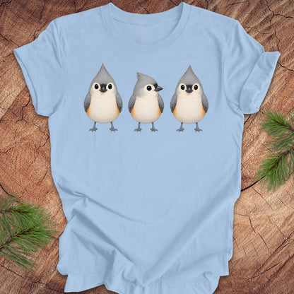 Blue t-shirt with 3 titmouses design on a wooden surface