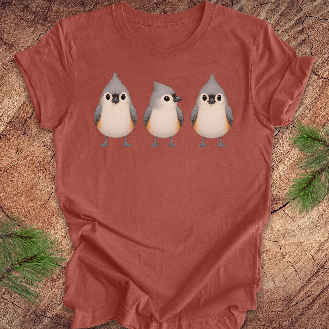 Clay colored t-shirt with 3 titmouses design on a wooden surface