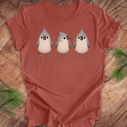 Clay colored t-shirt with 3 titmouses design on a wooden surface