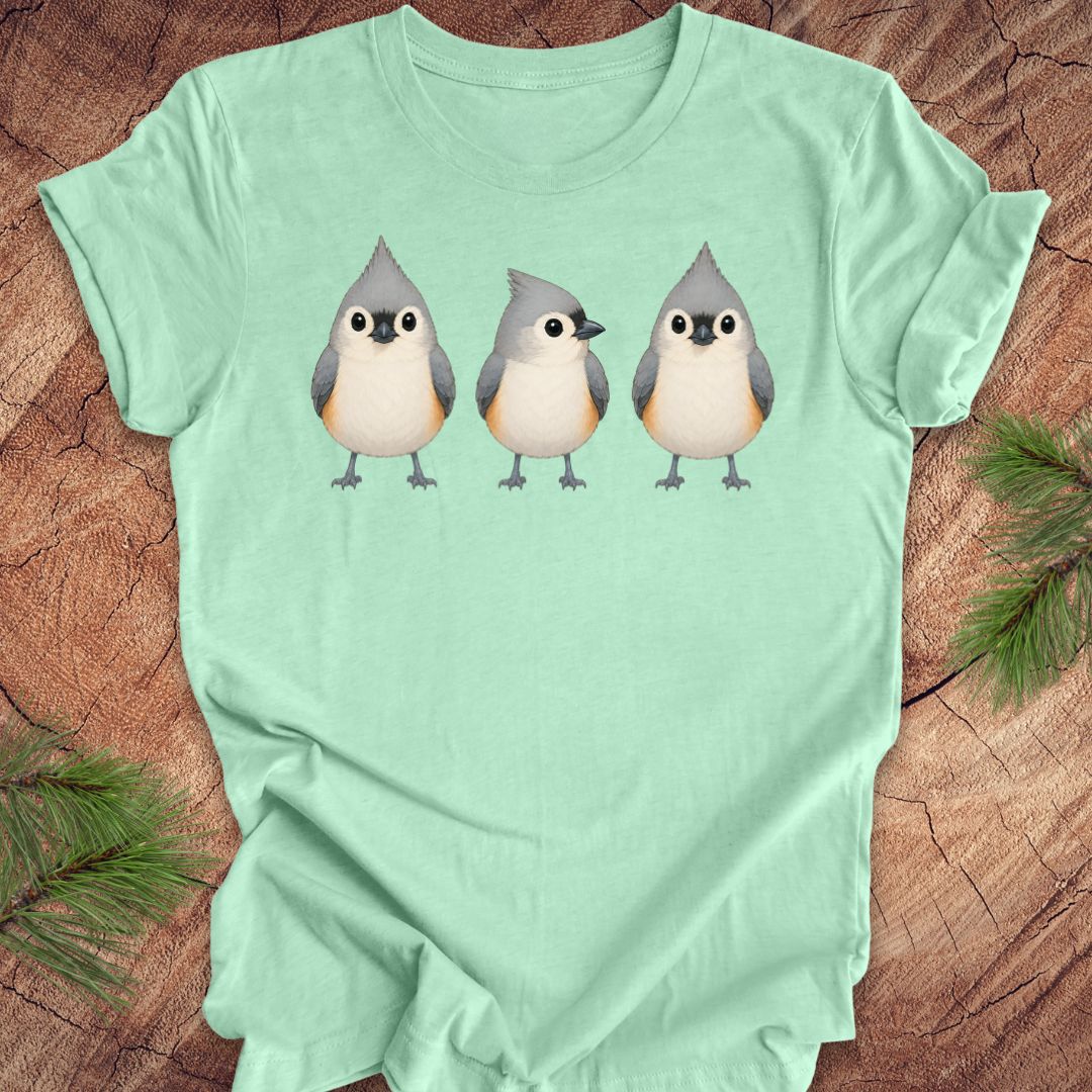Mint green t-shirt with 3 titmouses design on a wooden surface