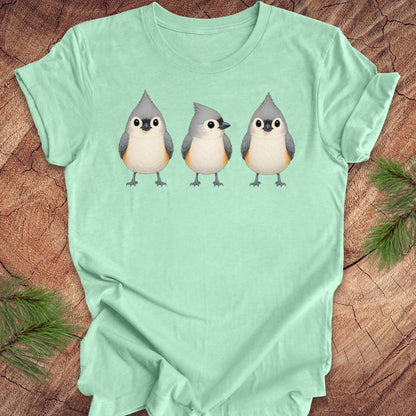 Mint green t-shirt with 3 titmouses design on a wooden surface