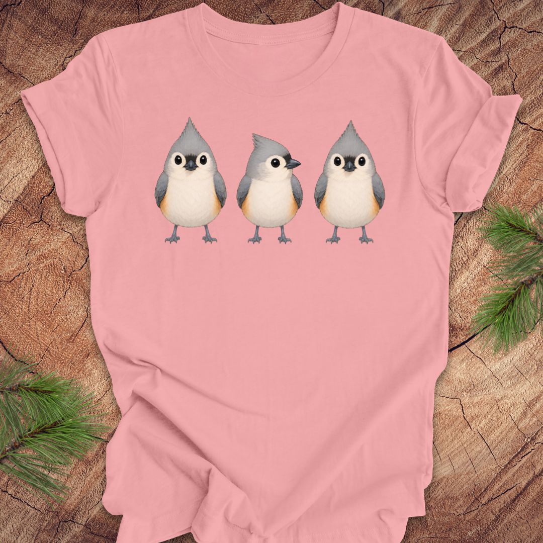 Pink t-shirt with 3 titmouses design on a wooden surface