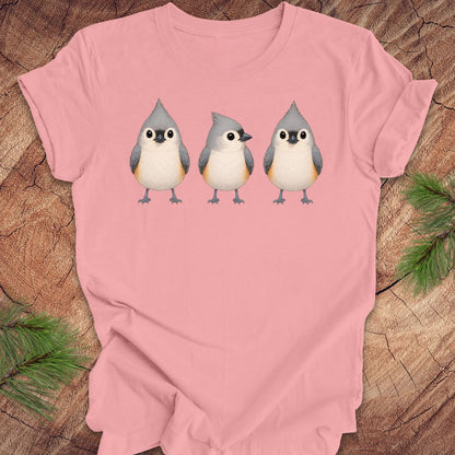 Pink t-shirt with 3 titmouses design on a wooden surface