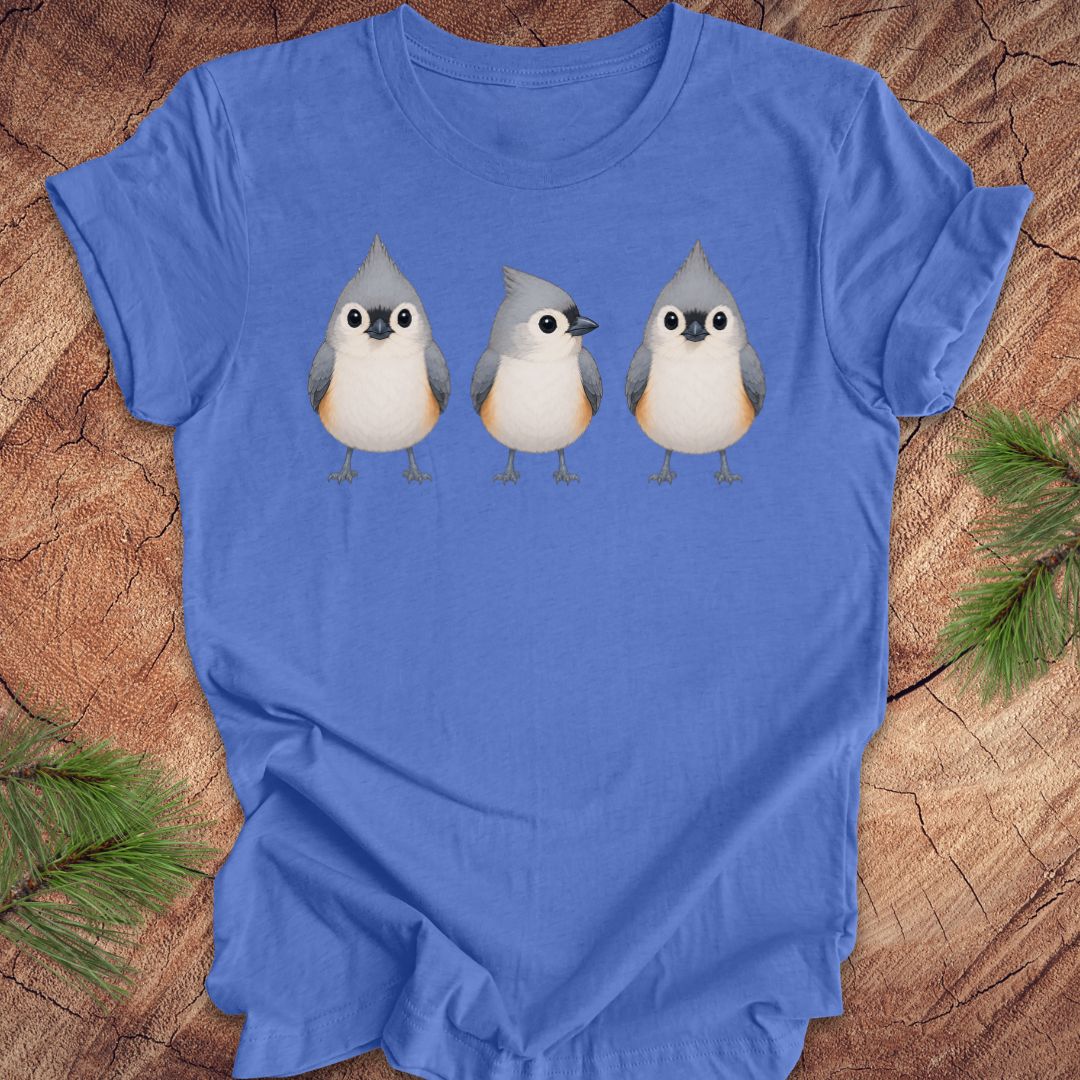 Blue t-shirt with 3 titmouses design on a wooden surface