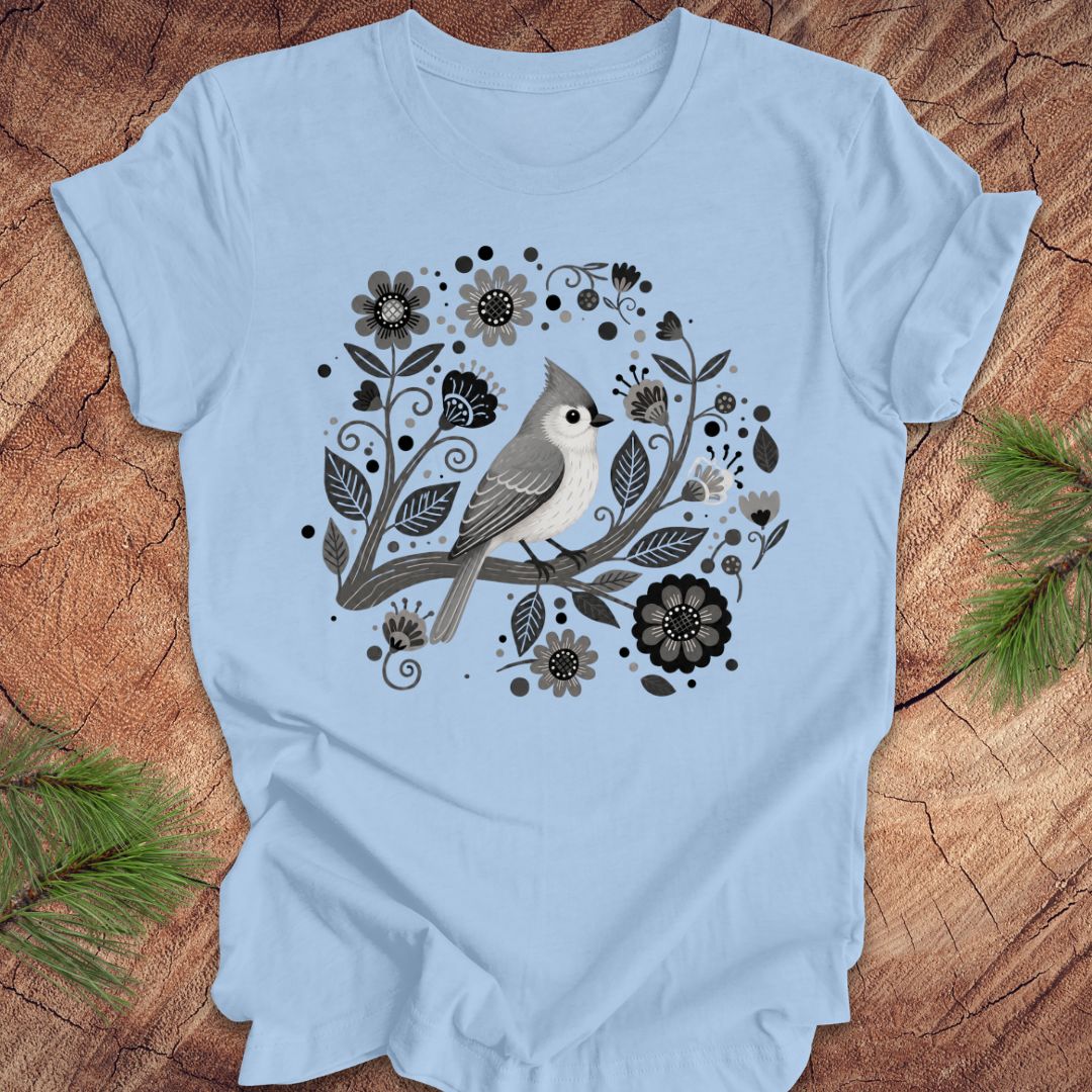 Light blue t-shirt with a titmouse bird and floral design on a wooden surface
