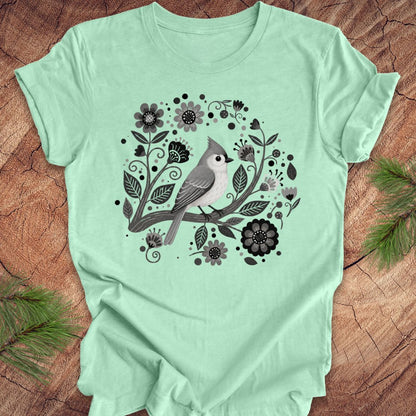 Mint green t-shirt with a titmouse bird and floral design on a wooden surface
