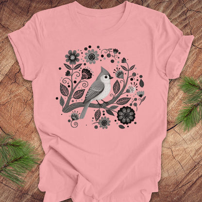 Pink t-shirt with a titmouse bird and floral design on a wooden surface