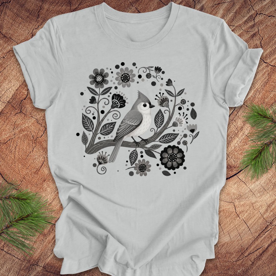 Gray t-shirt with a titmouse bird and floral design on a wooden surface