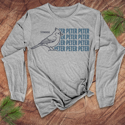 Gray long-sleeve shirt with a titmouse bird graphic and text on a wooden surface