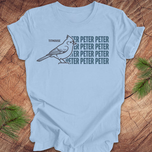 Blue t-shirt with titmouse bird graphic and 'Peter Peter' text on a wooden surface