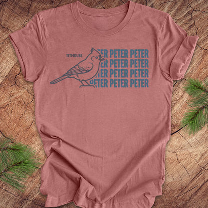 Mauve t-shirt with titmouse bird graphic and 'Peter Peter' text on a wooden surface