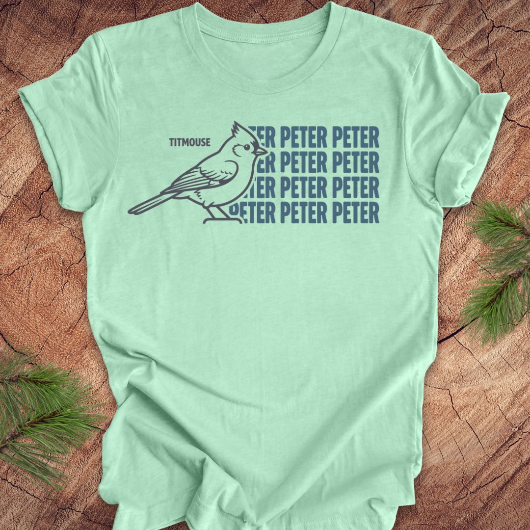 Mint green t-shirt with titmouse bird graphic and 'Peter Peter' text on a wooden surface