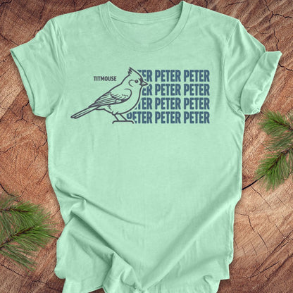 Mint green t-shirt with titmouse bird graphic and 'Peter Peter' text on a wooden surface