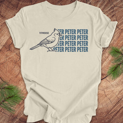 Beige t-shirt with titmouse bird graphic and 'Peter Peter' text on a wooden surface
