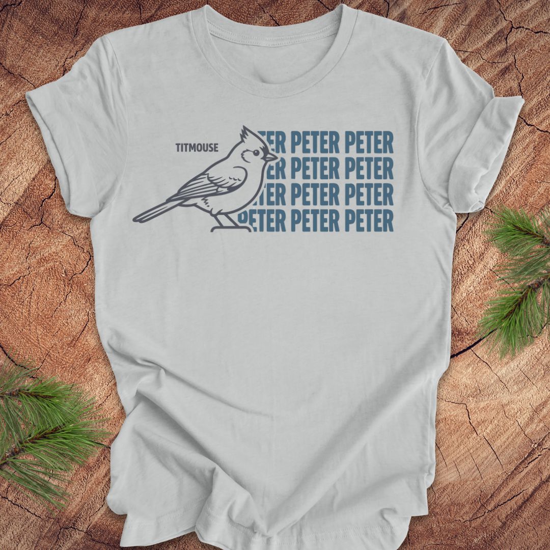 Gray t-shirt with titmouse bird graphic and 'Peter Peter' text on a wooden surface