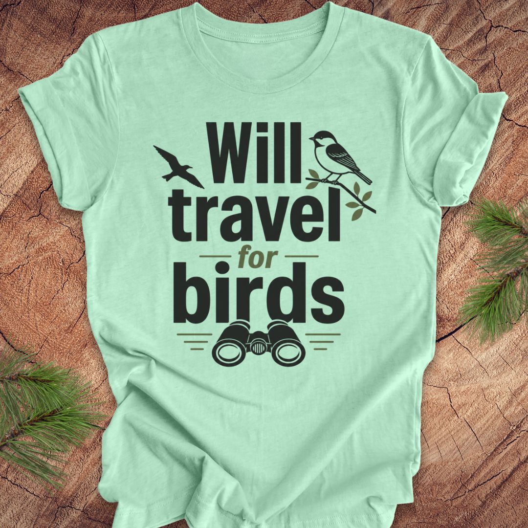 Mint green t-shirt with text, 'will travel for birds' on a wood background. 