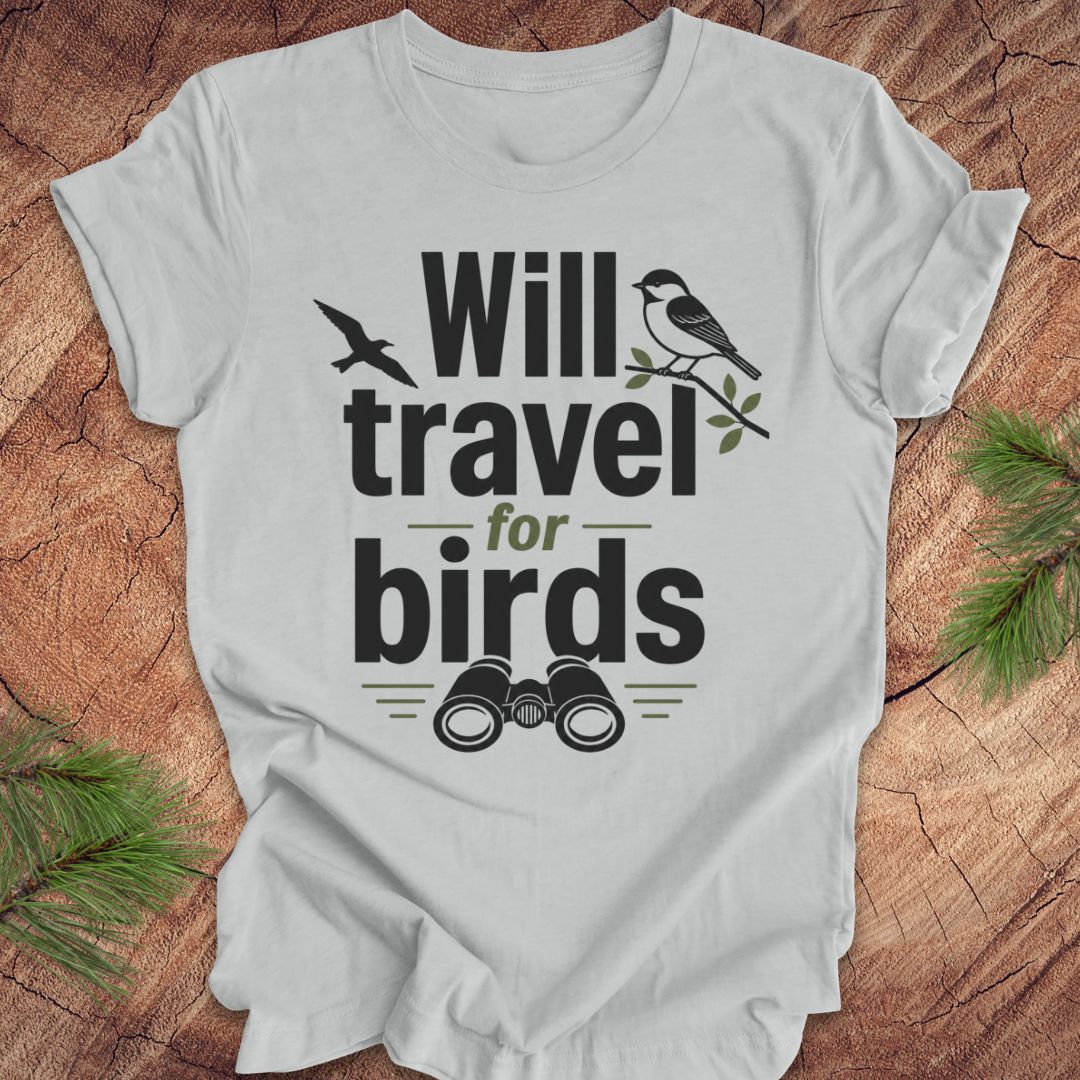 Gray t-shirt with text, 'will travel for birds' on a wood background. 