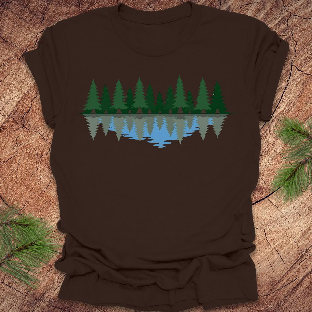 Brown t-shirt with a nature graphic of trees and water on a wooden surface.