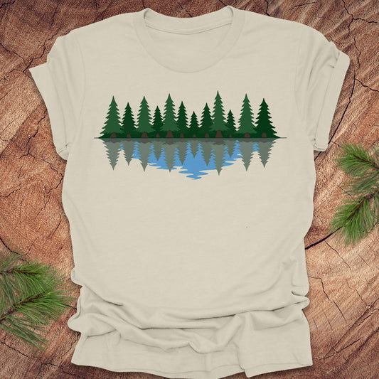 Beige t-shirt with a graphic of trees reflected in water on a wooden surface.