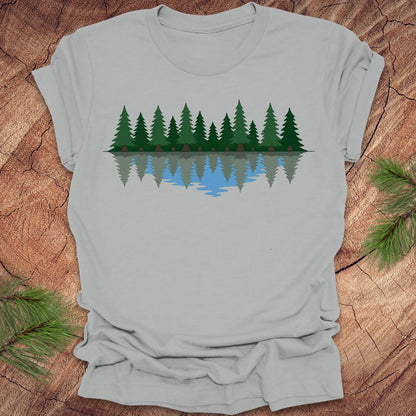 Gray t-shirt with a forest design on a wooden surface