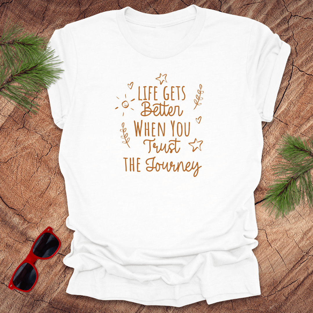 white tshirt with text life gets better when you trust the journey, on a wood background