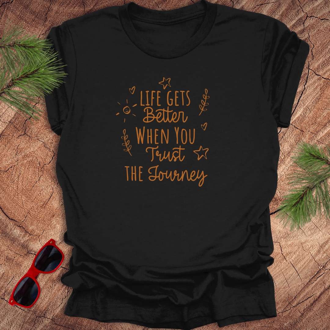 black tshirt with text life gets better when you trust the journey, on a wood background