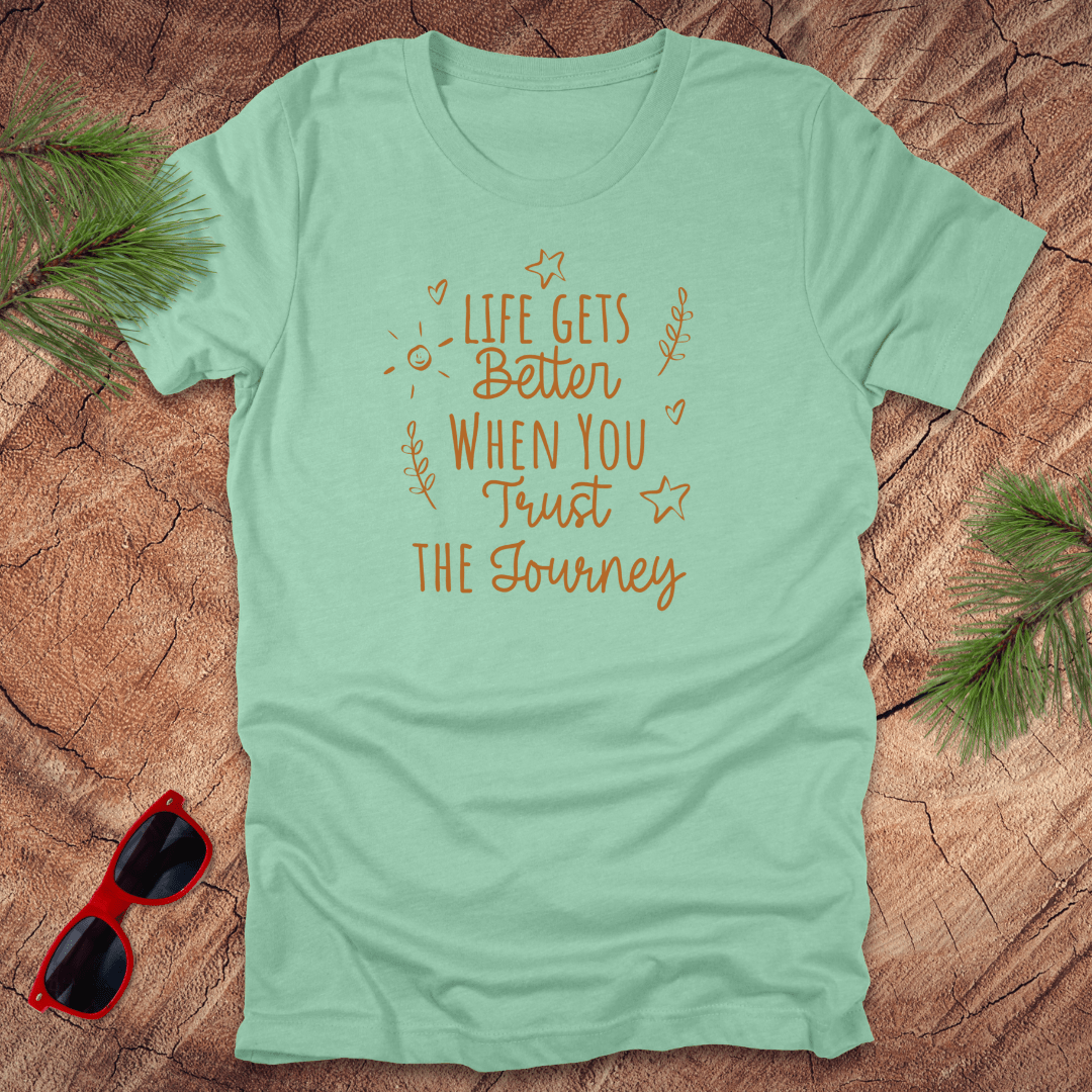 mint green tshirt with text life gets better when you trust the journey, on a wood background