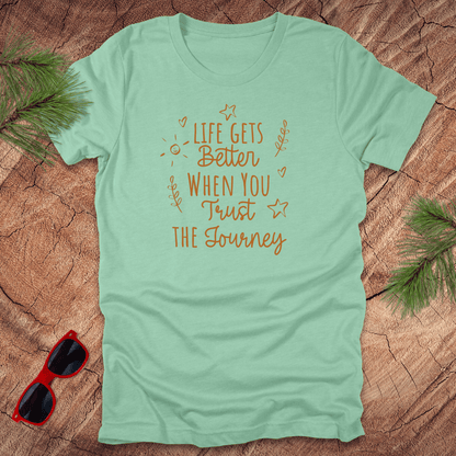 mint green tshirt with text life gets better when you trust the journey, on a wood background