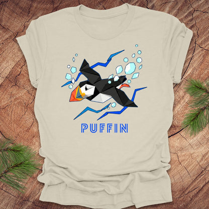 Beige t-shirt with a puffin graphic and 'PUFFIN' text on a wooden surface.