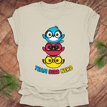 Beige t-shirt with colorful bird design and 'Team Bird Nerd' text on a wooden surface.