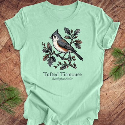 Light green t-shirt with a tufted titmouse illustration on a wooden surface