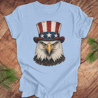 Light blue t-shirt with an eagle wearing an Uncle Sam hat on a wooden surface